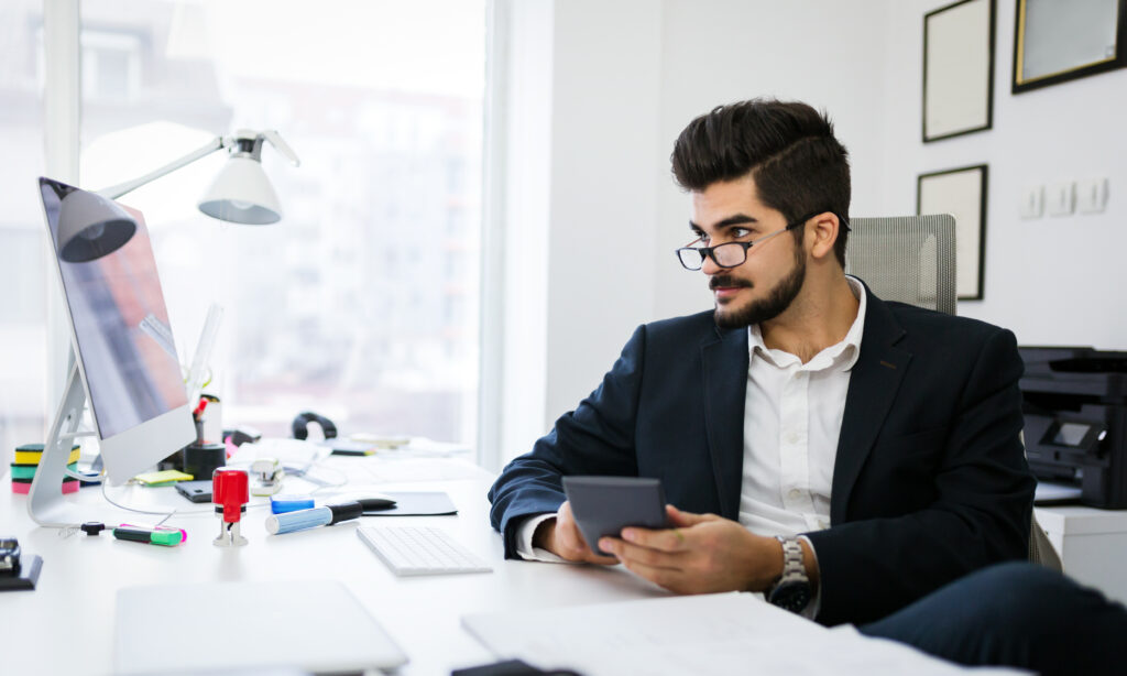 Picture of busy man using calculator in office doing report